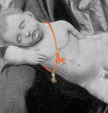 il ciondolo del bambino rimanda alla vita, alla morte e alla futura resurrezione di Cristo.